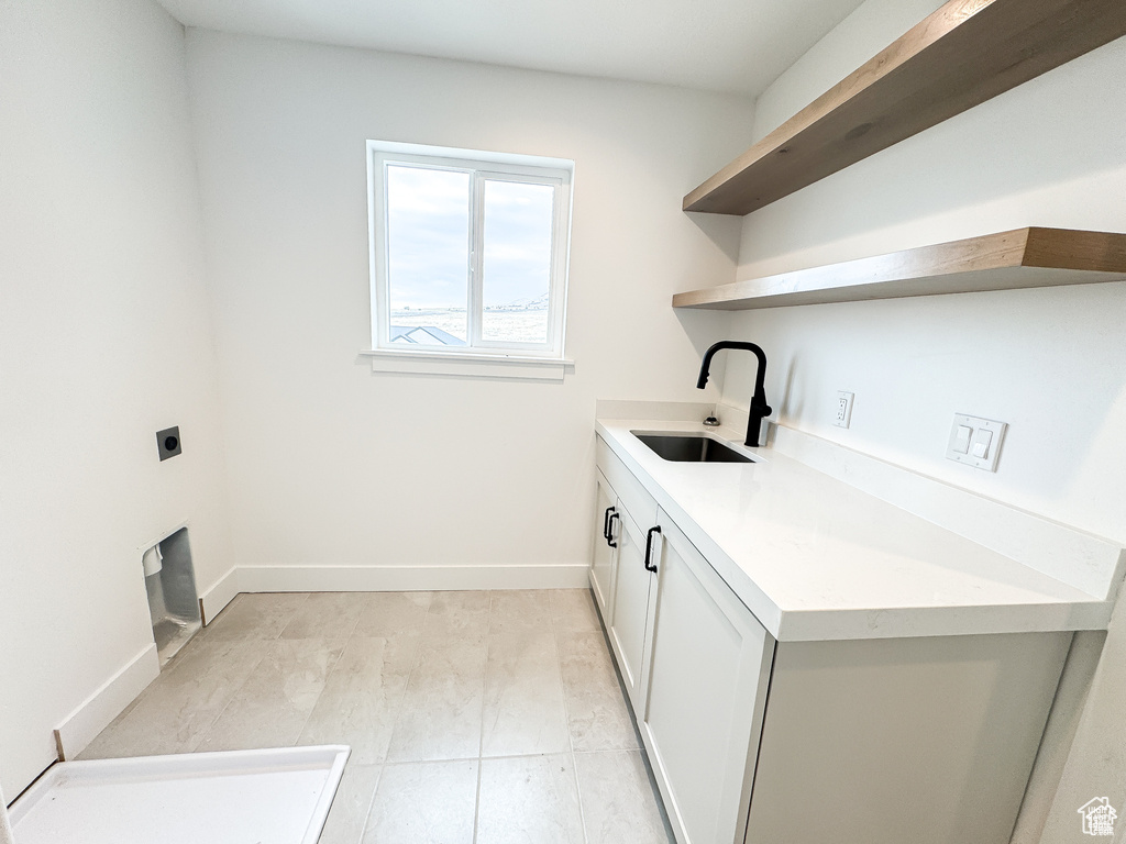 Laundry room with a sink, hookup for an electric dryer, and baseboards