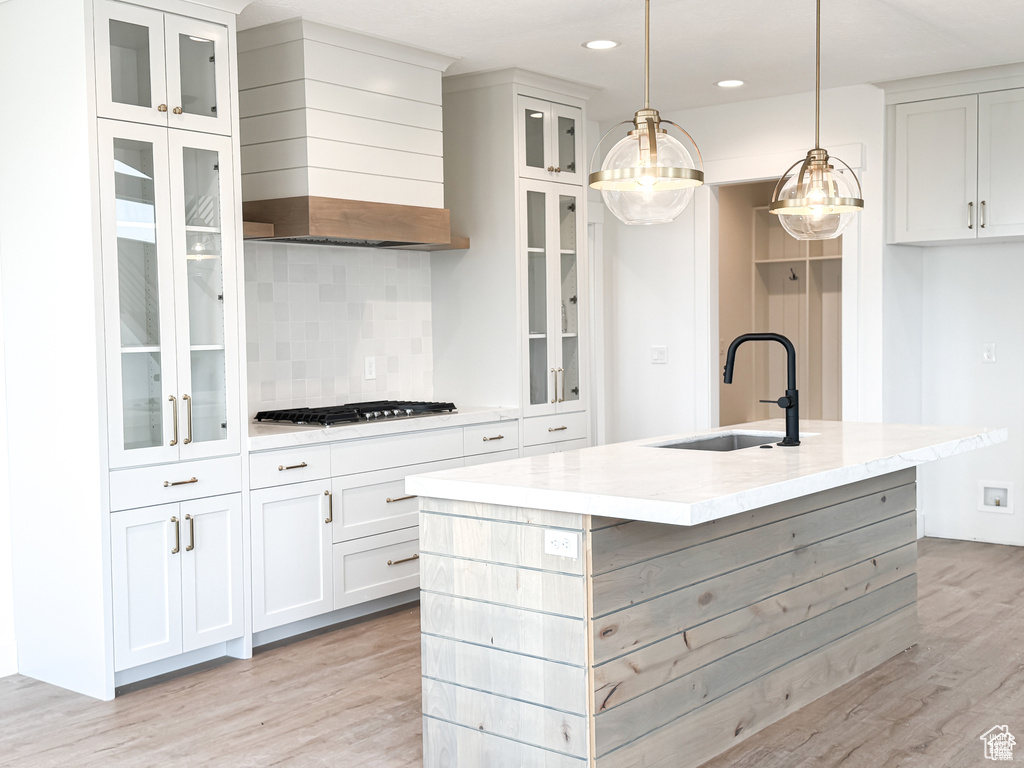 Kitchen with a sink, wall chimney exhaust hood, stainless steel gas stovetop, light wood-style floors, and recessed lighting