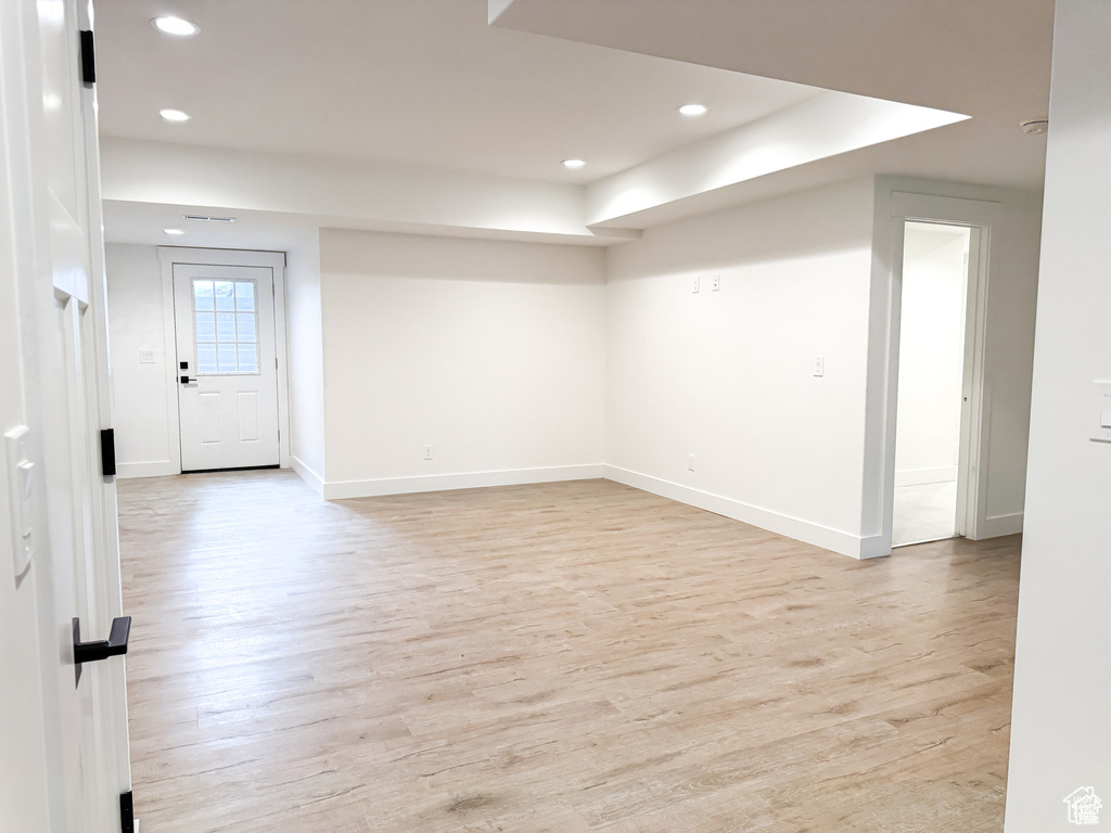Spare room featuring light wood finished floors, recessed lighting, baseboards, and a raised ceiling