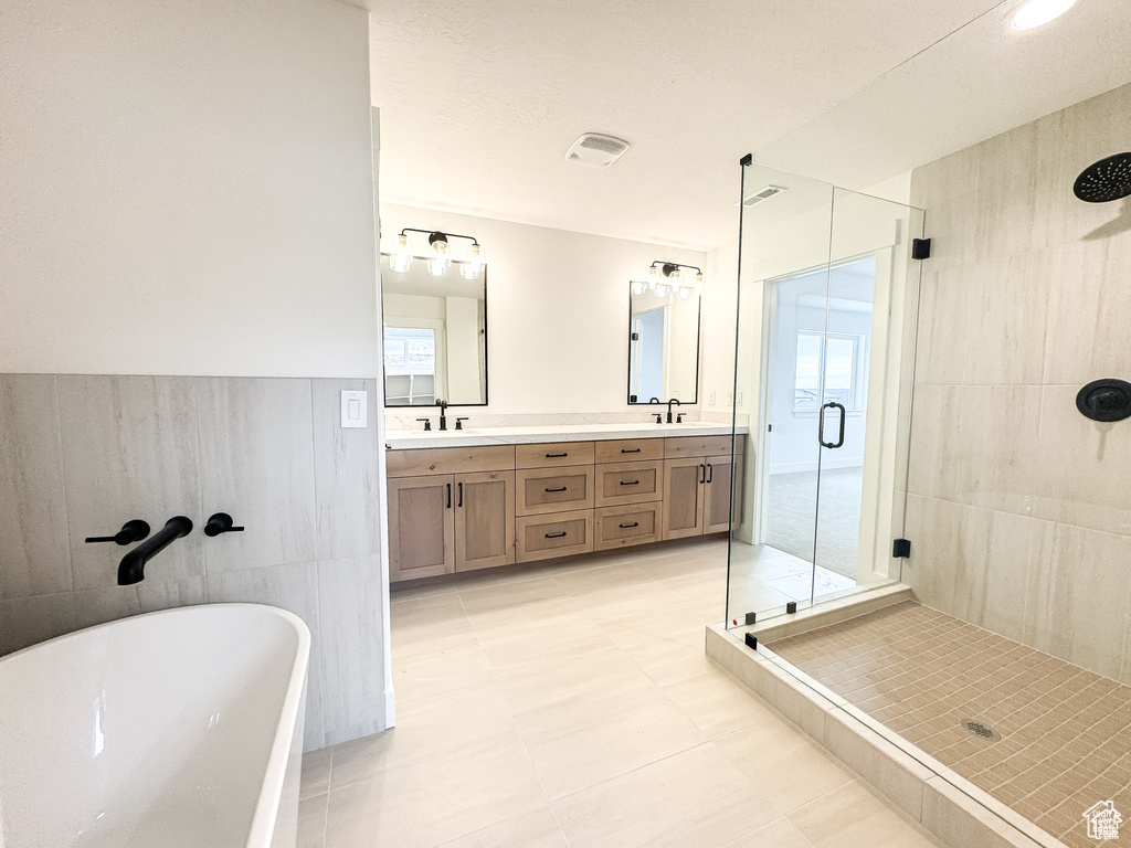 Bathroom featuring a shower stall, a soaking tub, and double vanity