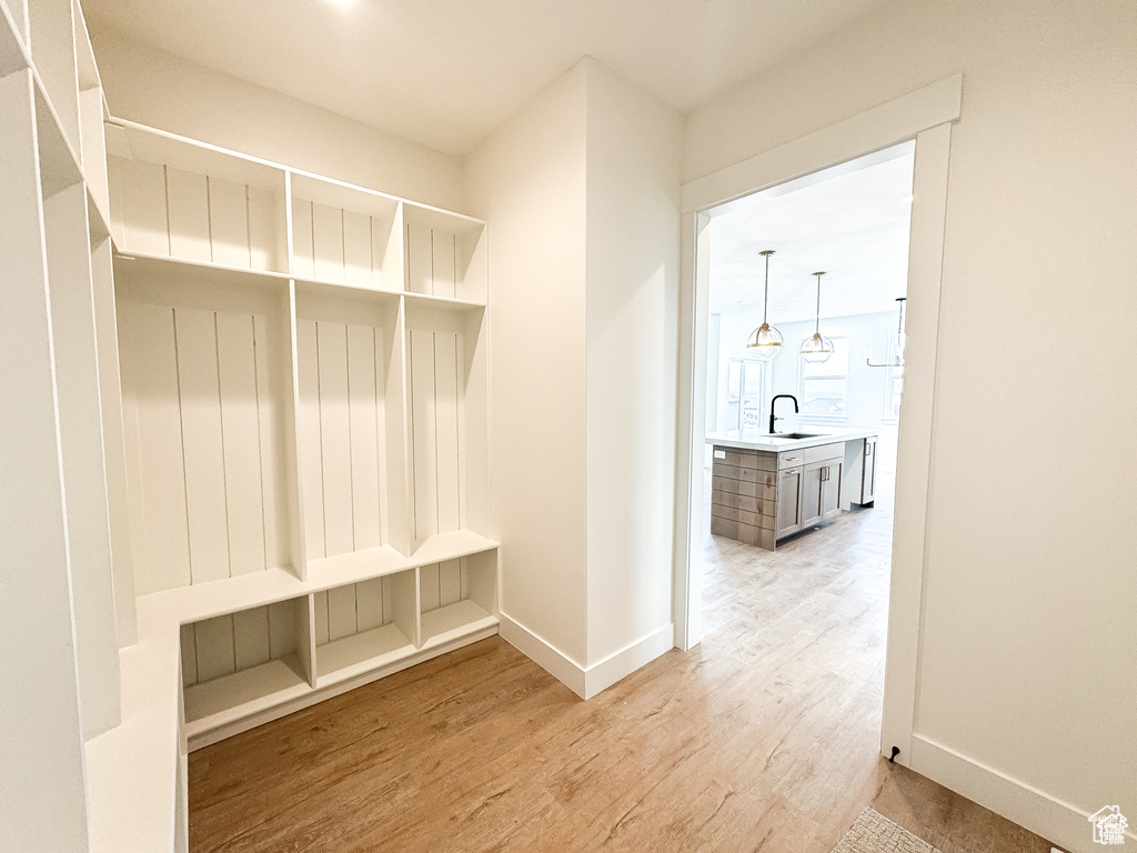 Mudroom with a sink, light wood finished floors, and baseboards