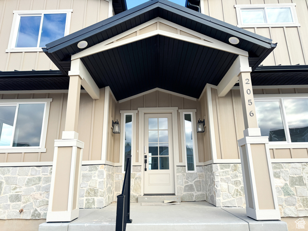 Property entrance featuring stone siding, board and batten siding, metal roof, and covered porch