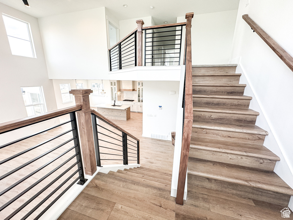 Staircase featuring wood finished floors and a high ceiling