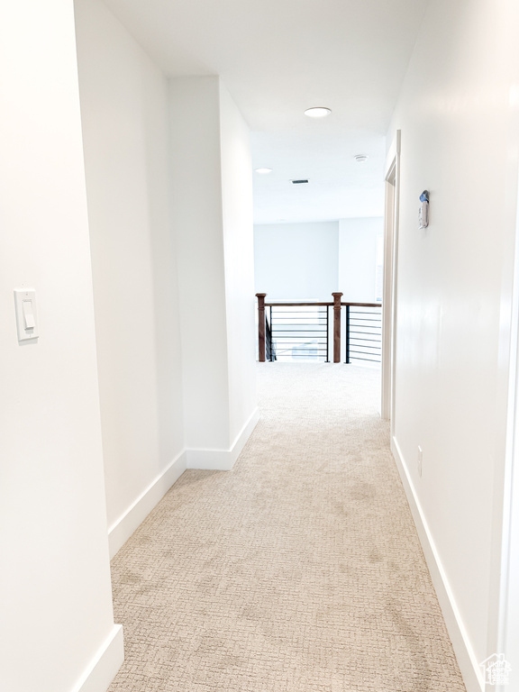Hallway with carpet floors, baseboards, recessed lighting, and an upstairs landing