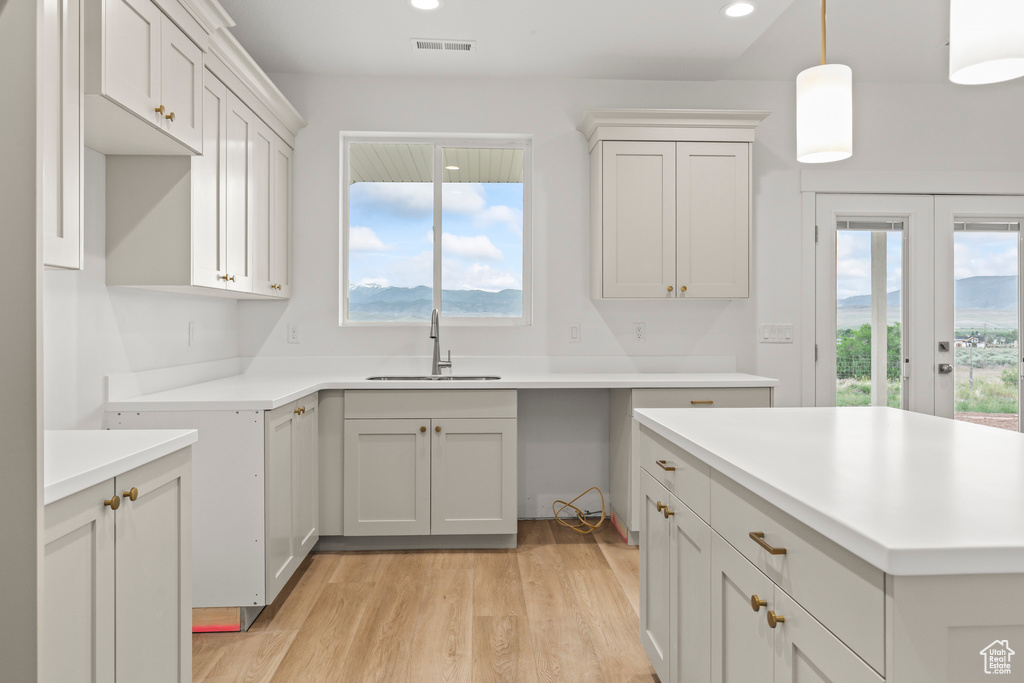 Kitchen with a sink, light wood-type flooring, french doors, recessed lighting, and pendant lighting
