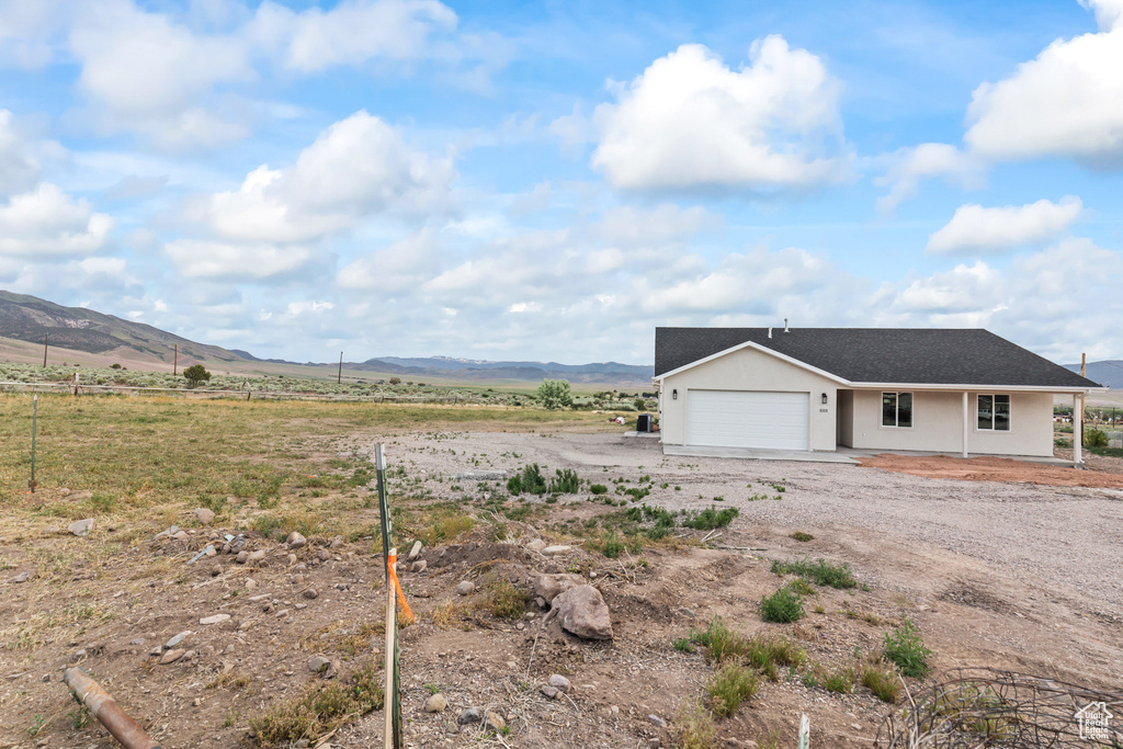 Exterior space featuring a mountain view, a garage, stucco siding, a rural view, and driveway