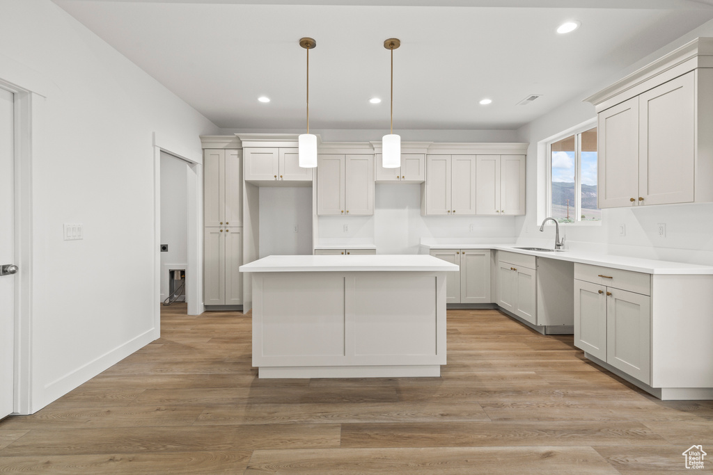Kitchen with a sink, a kitchen island, recessed lighting, pendant lighting, and light wood finished floors