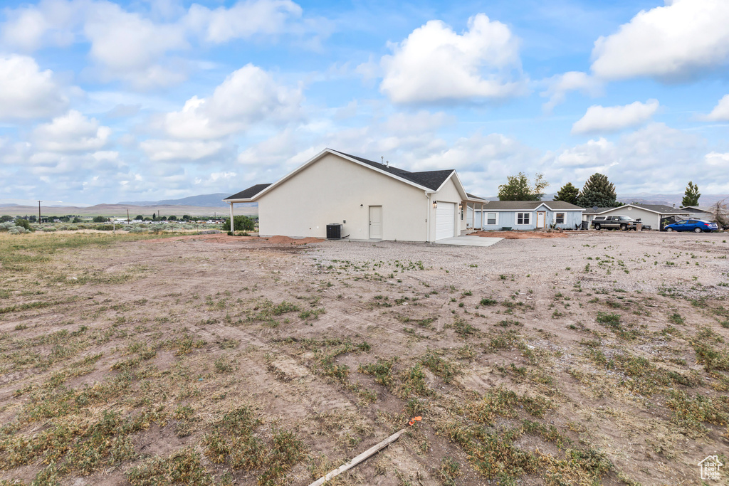 View of side of property featuring an attached garage, stucco siding, and cooling unit