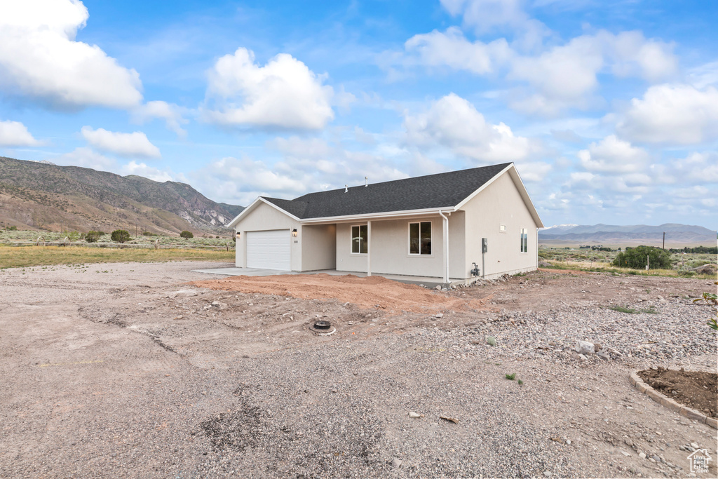 Ranch-style house with a mountain view, a garage, and stucco siding