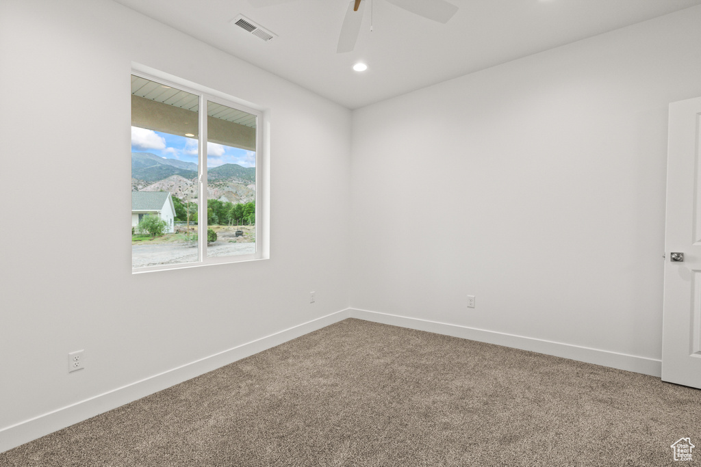 Carpeted empty room featuring a ceiling fan, baseboards, a mountain view, and recessed lighting