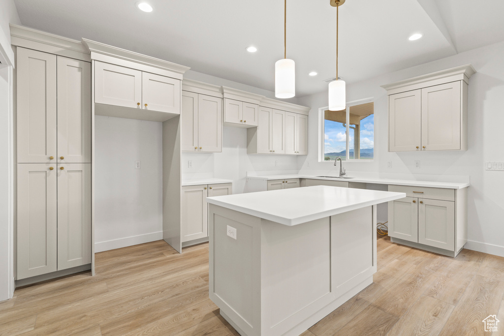 Kitchen featuring a kitchen island, a sink, light wood finished floors, recessed lighting, and baseboards