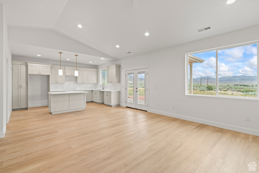 Unfurnished living room featuring lofted ceiling, recessed lighting, light wood finished floors, baseboards, and a mountain view