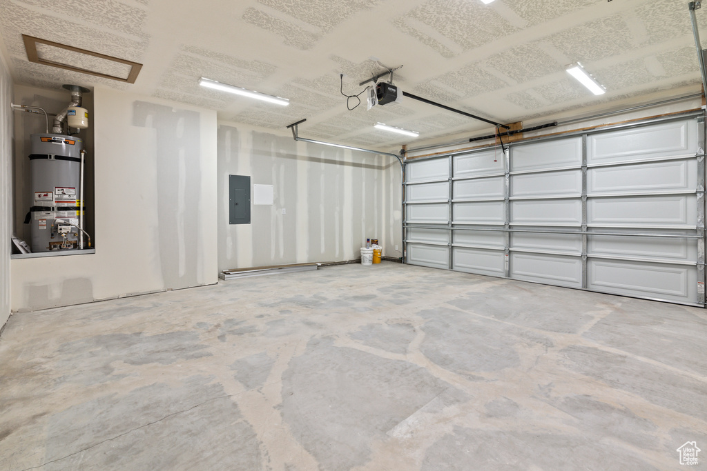 Garage featuring water heater, a garage door opener, and electric panel