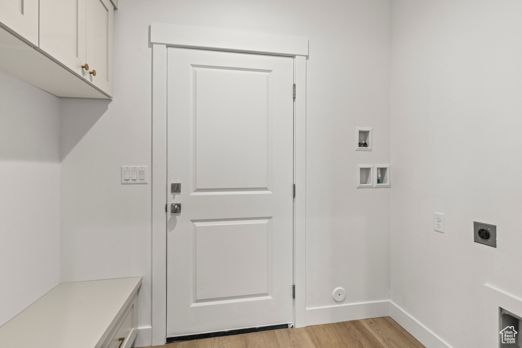 Laundry area featuring electric dryer hookup, washer hookup, cabinet space, light wood finished floors, and baseboards