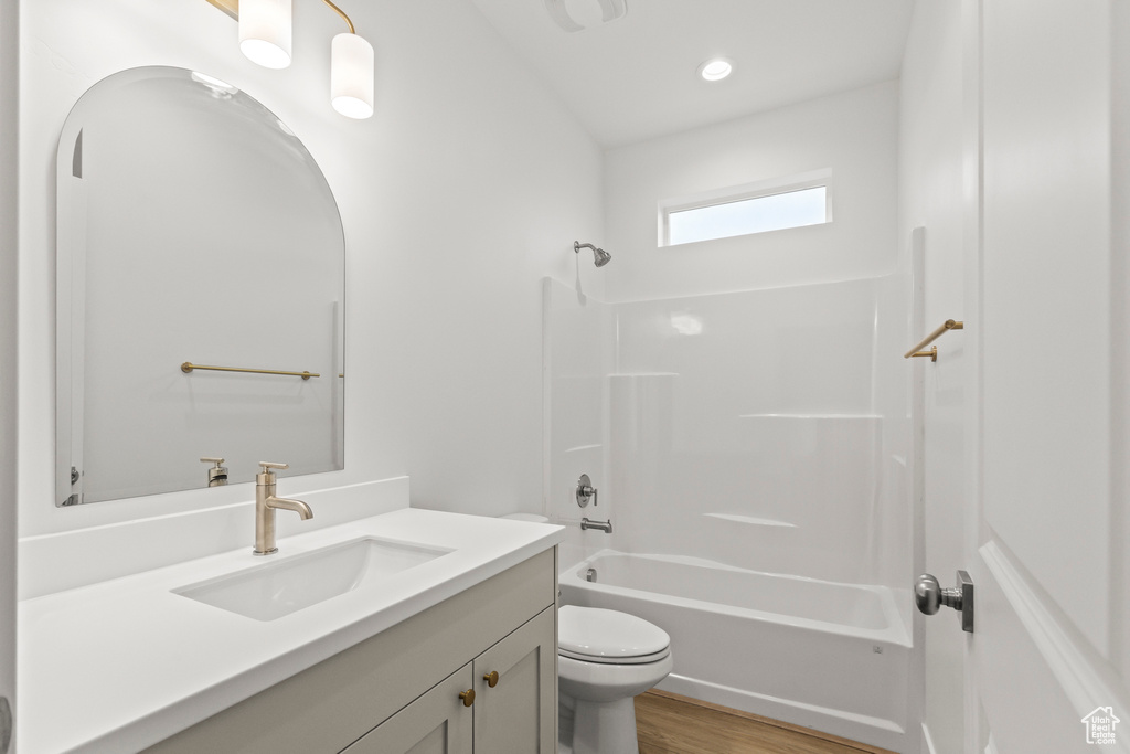 Bathroom featuring vanity, toilet,  shower combination, wood finished floors, and recessed lighting