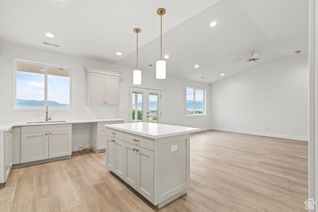 Kitchen featuring a sink, lofted ceiling, light wood finished floors, decorative light fixtures, and ceiling fan