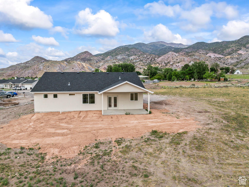 Rear view of house featuring french doors, a mountain view, a patio area, stucco siding, and a shingled roof