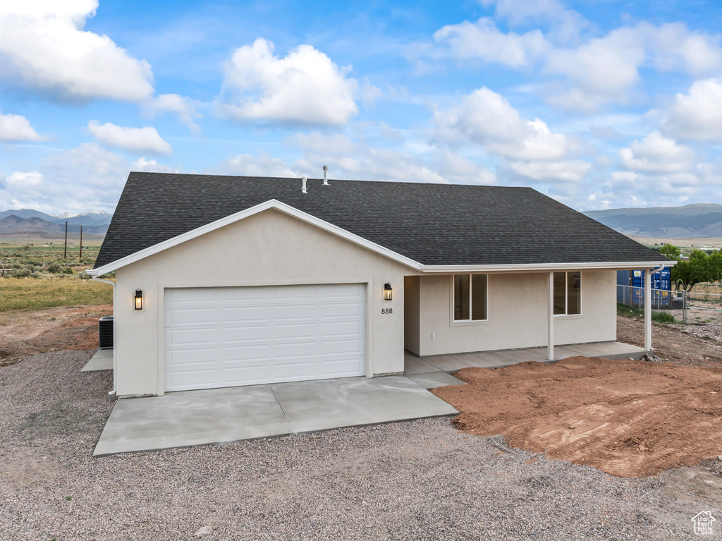 View of front of house featuring roof with shingles, a mountain view, stucco siding, and driveway