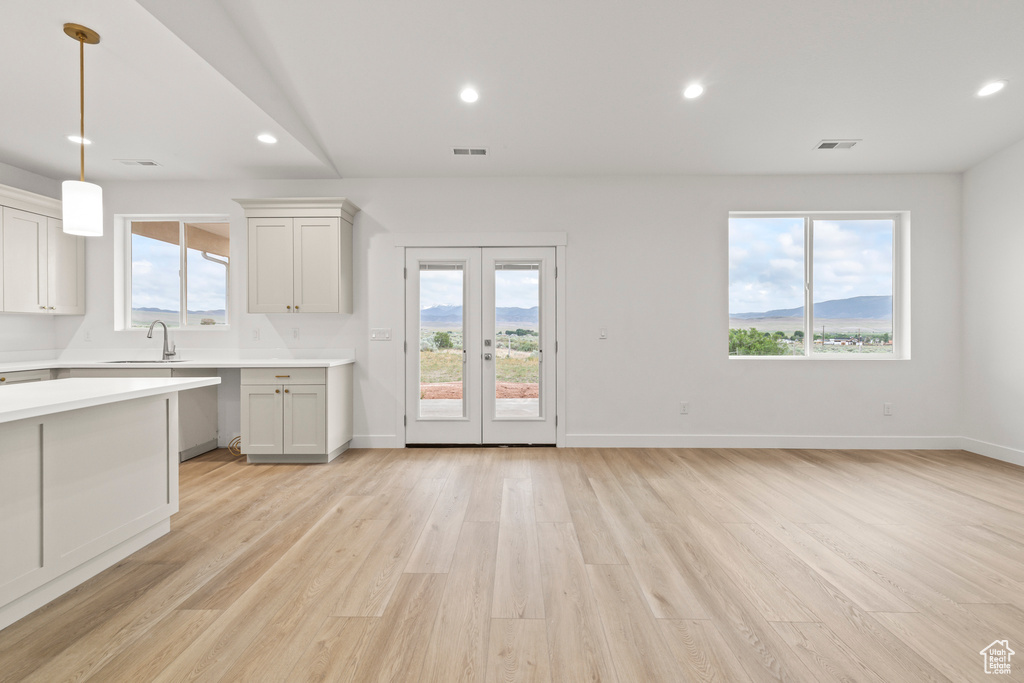 Kitchen featuring light countertops, light wood-type flooring, hanging light fixtures, a sink, and recessed lighting