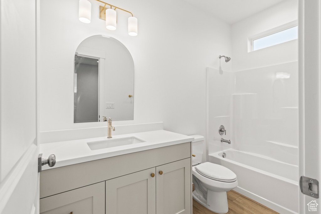 Full bathroom with vanity, wood finished floors, toilet, and shower / washtub combination
