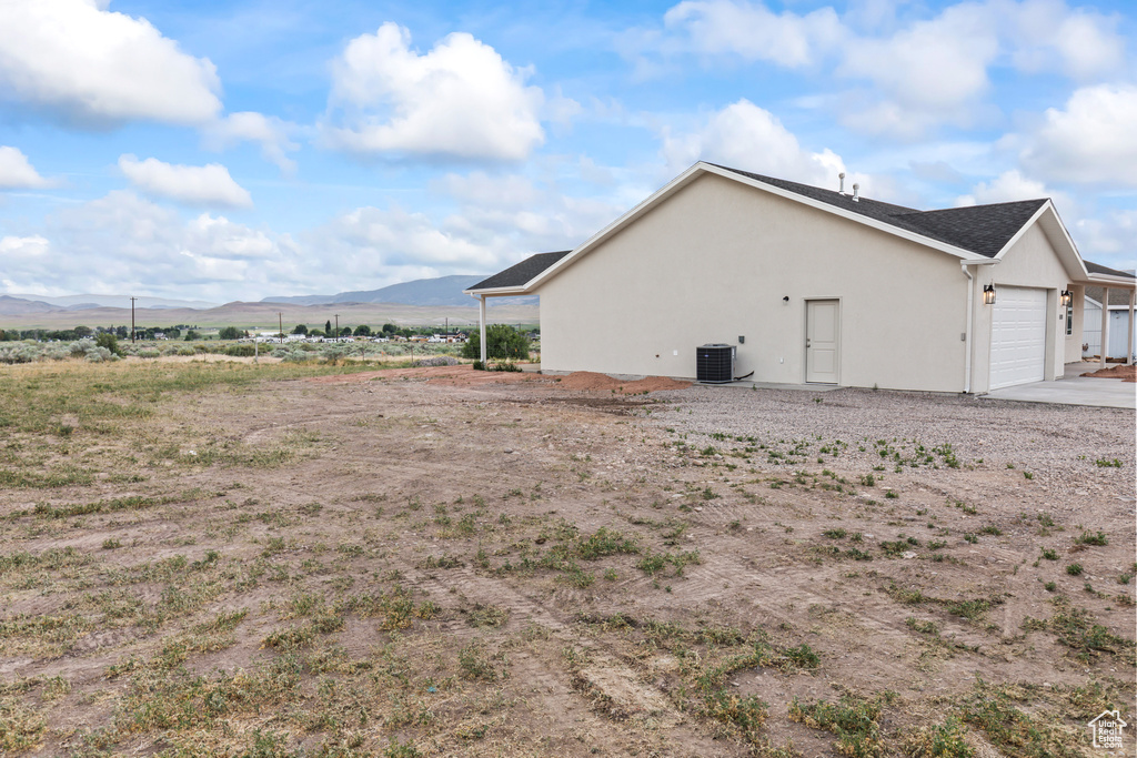View of side of property featuring a mountain view, a garage, stucco siding, and driveway