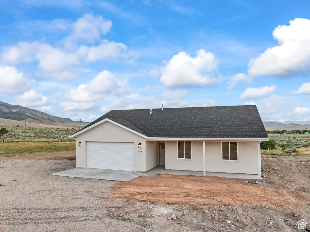 Ranch-style house featuring a mountain view, a garage, and stucco siding