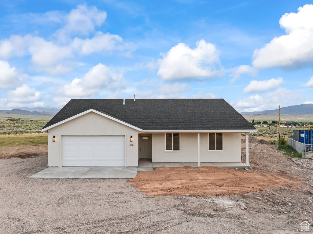 View of front of house with a mountain view, a shingled roof, a garage, driveway, and covered porch