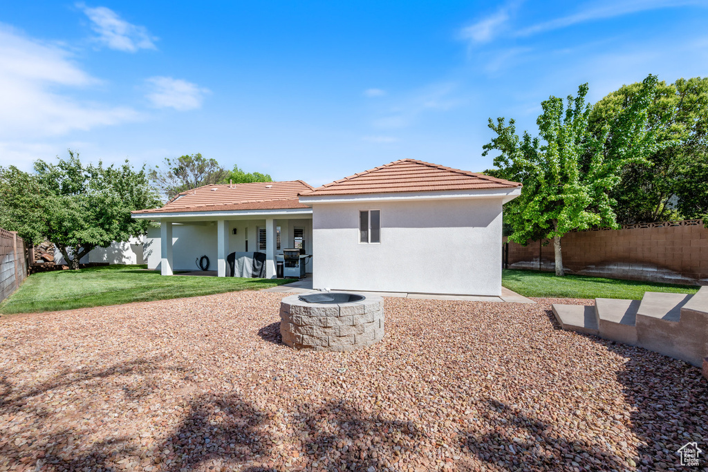 Rear view of house with a fire pit, stucco siding, a tiled roof, and a patio area