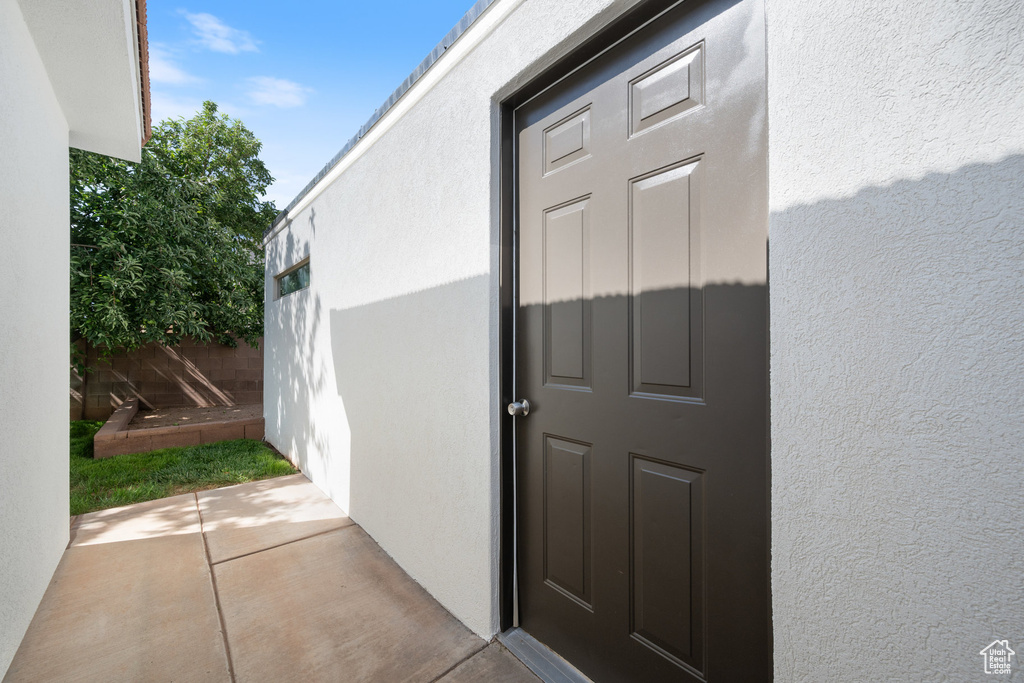 View of exterior entry featuring stucco siding and a patio area
