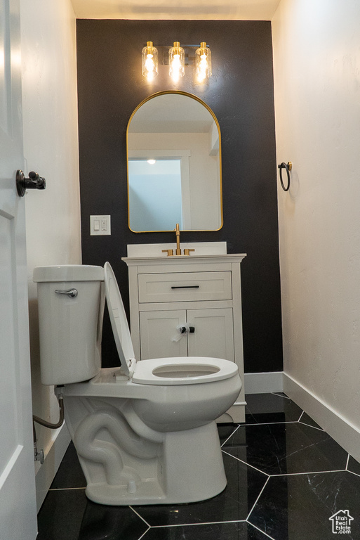 Bathroom with toilet, baseboards, and vanity