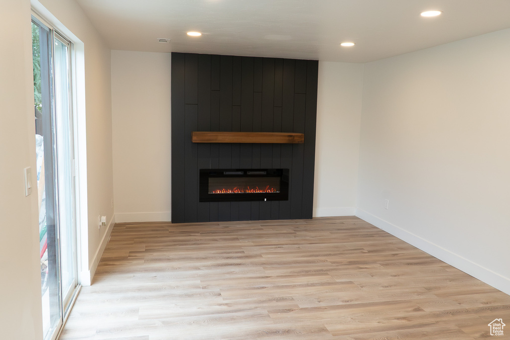 Detailed view of recessed lighting, wood finished floors, a fireplace, and baseboards