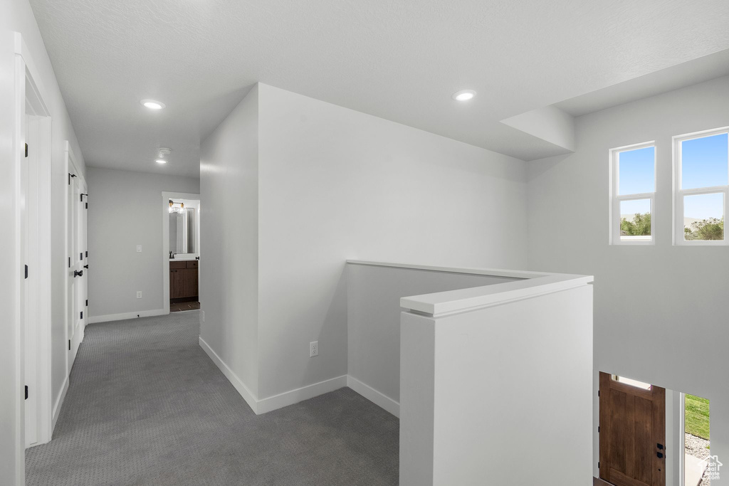 Hallway with an upstairs landing, carpet, baseboards, and recessed lighting