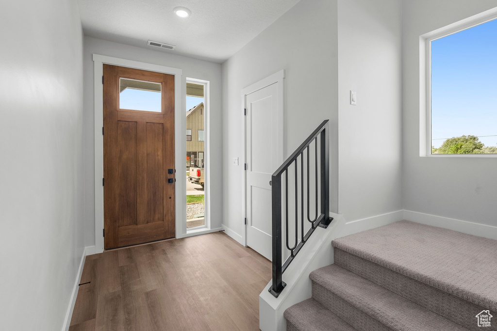 Entryway featuring wood finished floors, baseboards, and stairs