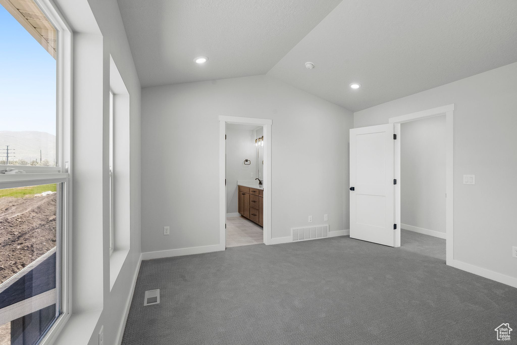 Unfurnished bedroom featuring carpet flooring, lofted ceiling, baseboards, ensuite bathroom, and recessed lighting