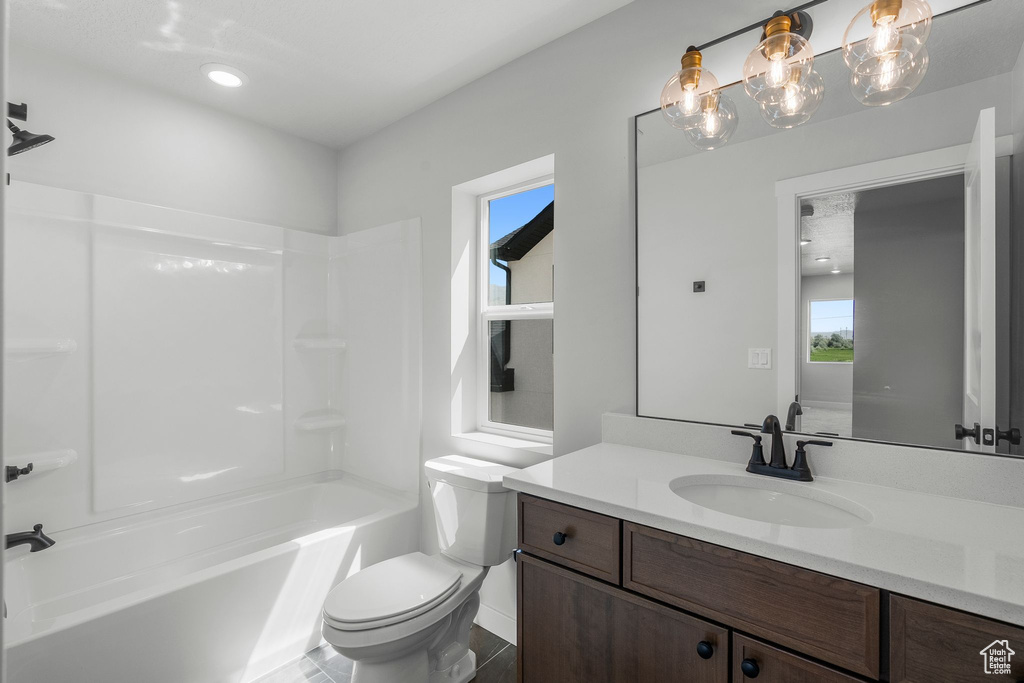 Bathroom featuring vanity, healthy amount of natural light, toilet, and washtub / shower combination