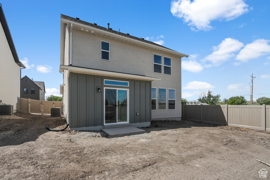 Back of house featuring board and batten siding, central AC, and a fenced backyard