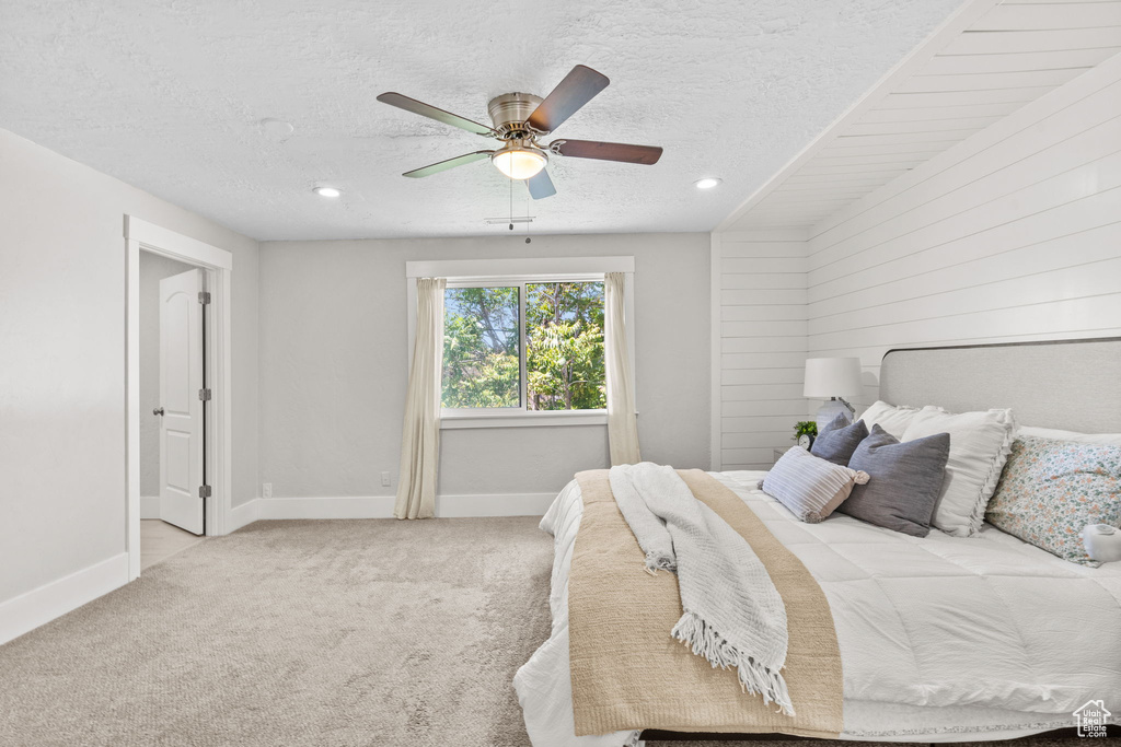 Carpeted bedroom featuring a textured ceiling, baseboards, a ceiling fan, recessed lighting, and wood walls
