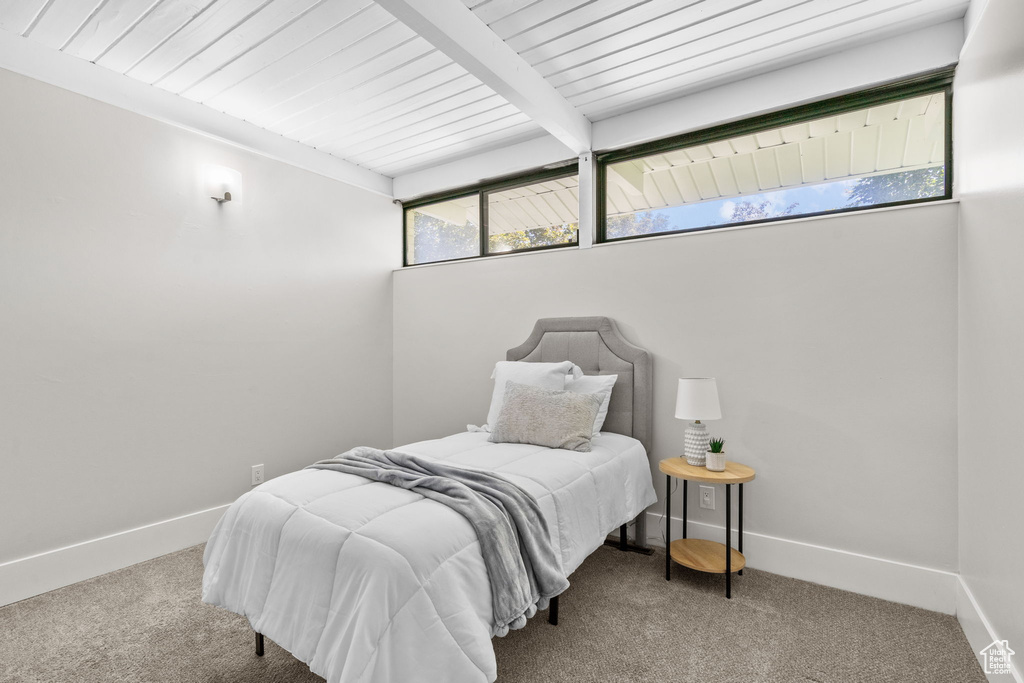 Bedroom with carpet flooring, baseboards, and wooden ceiling with exposed beams