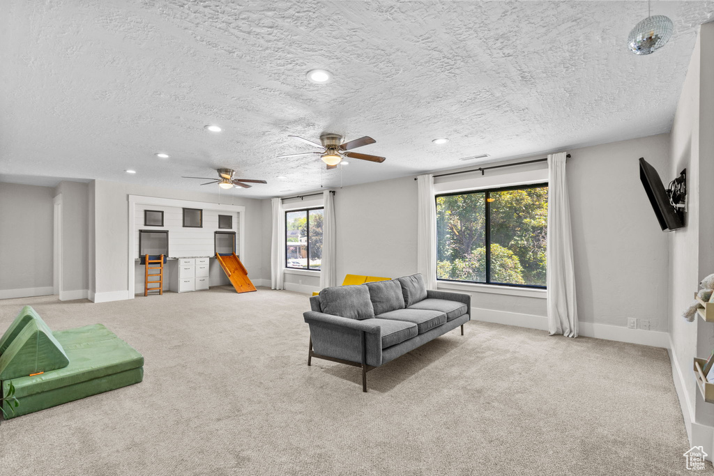 Carpeted living room featuring baseboards, a textured ceiling, recessed lighting, and ceiling fan