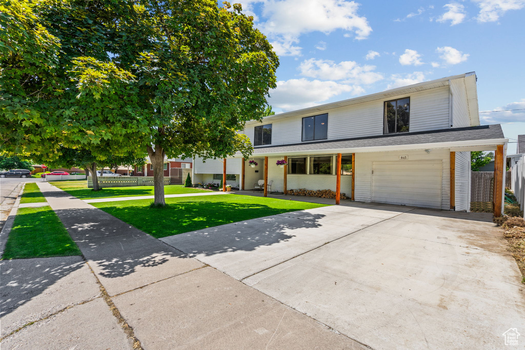 View of front of home with a front lawn, an attached garage, and driveway