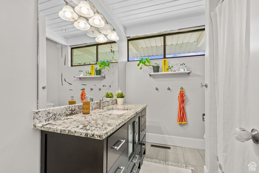 Bathroom featuring vanity, baseboards, a shower with shower curtain, and toilet