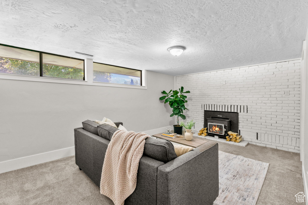 Carpeted living area featuring baseboards, a brick fireplace, and a textured ceiling