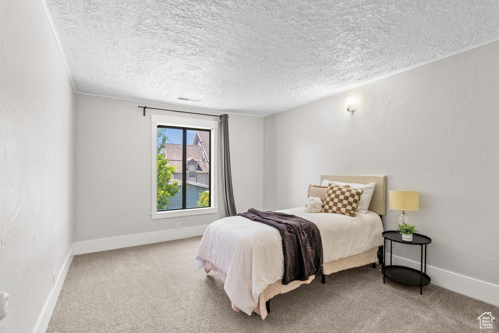Carpeted bedroom featuring a textured ceiling and baseboards