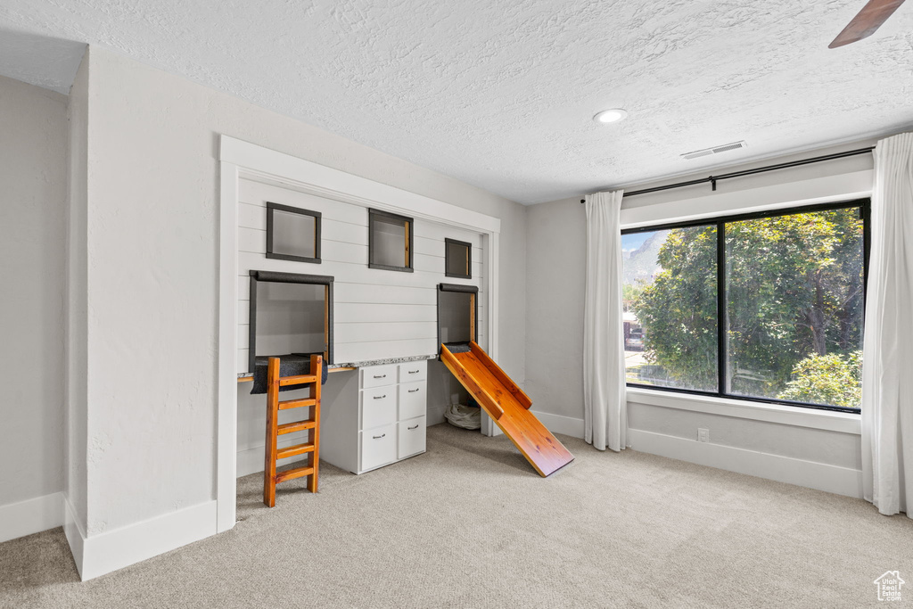 Unfurnished bedroom featuring light colored carpet, a textured ceiling, and baseboards