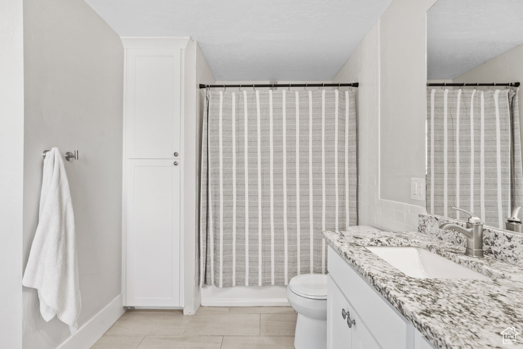 Full bathroom with vanity, toilet, tile patterned floors, and curtained shower