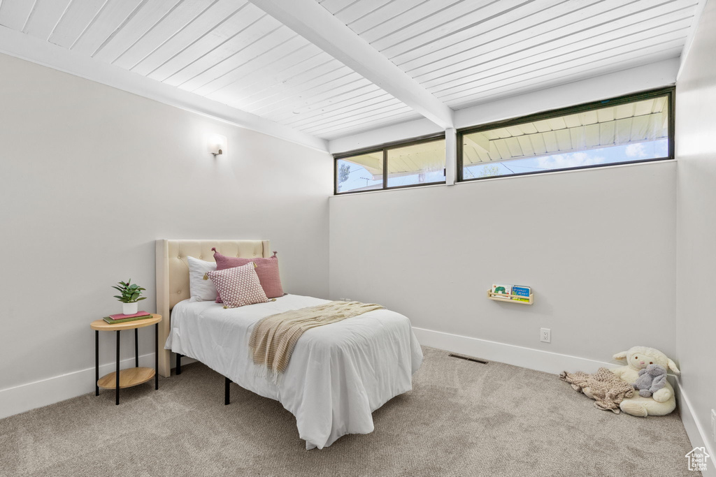 Carpeted bedroom featuring baseboards and wood ceiling with exposed beams
