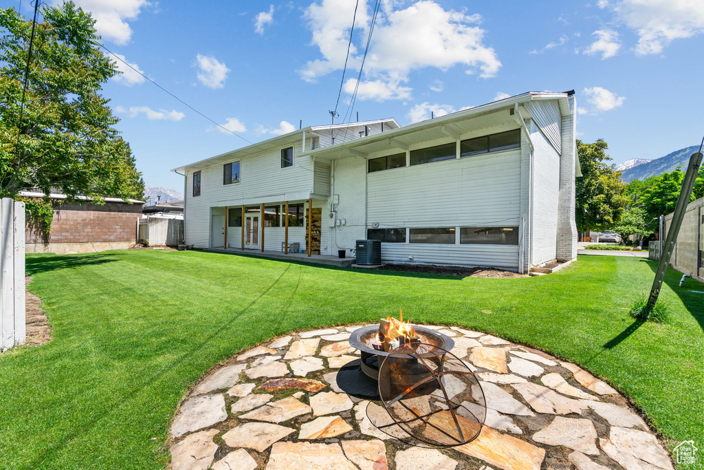 Rear view of property featuring a fire pit, a patio, and central AC unit