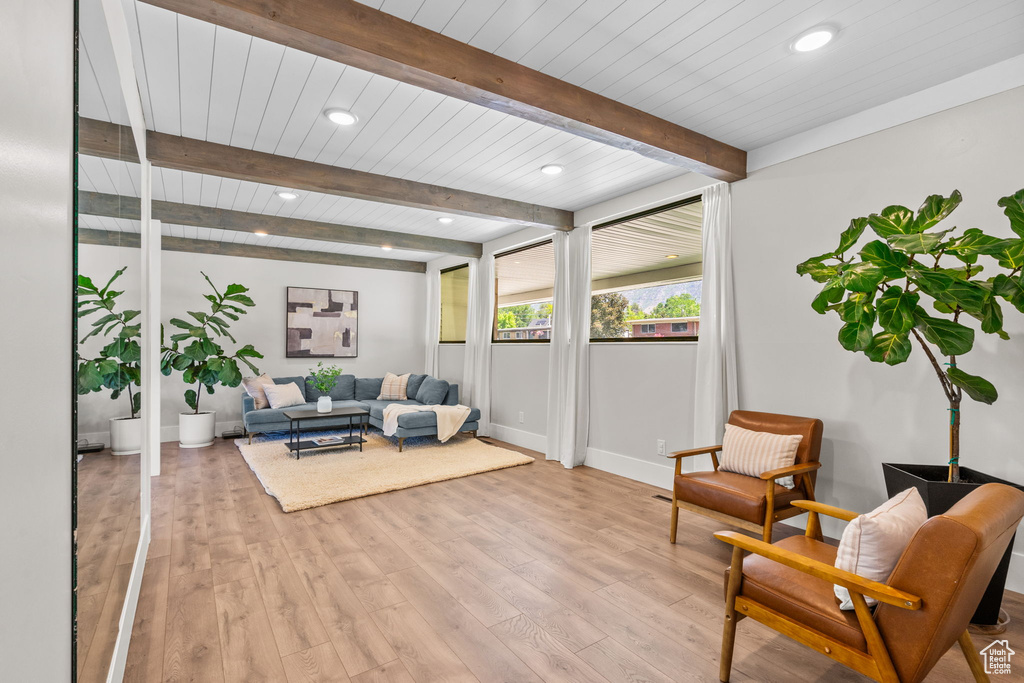 Living area featuring light wood-style flooring, recessed lighting, beamed ceiling, and baseboards
