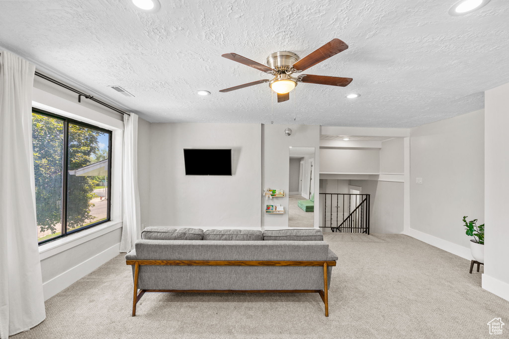 Carpeted living area with recessed lighting, ceiling fan, baseboards, and a textured ceiling