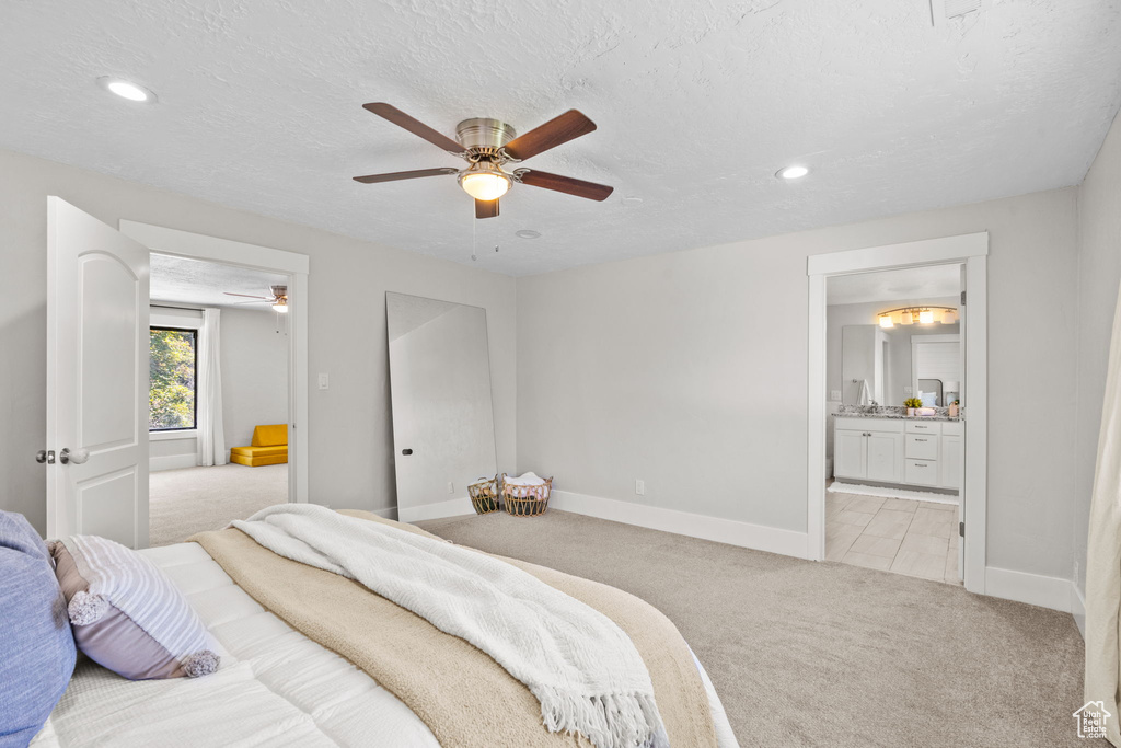 Bedroom featuring light carpet, baseboards, recessed lighting, ensuite bathroom, and a textured ceiling